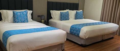 Habitación de hotel con dos camas, suelo de madera y diseño moderno.