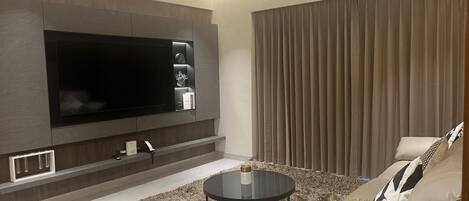 A modern living room with a flat-screen TV, a round coffee table, and a sofa.