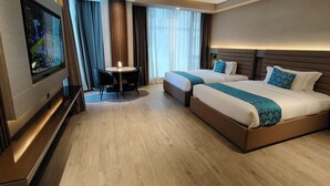 A hotel room with two beds, a TV, a small table, and a window with curtains. - Bayprime Hotel  (Parañaque)