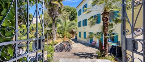 Un patio con una verja de metal, bicicletas y un edificio con contraventanas azules.