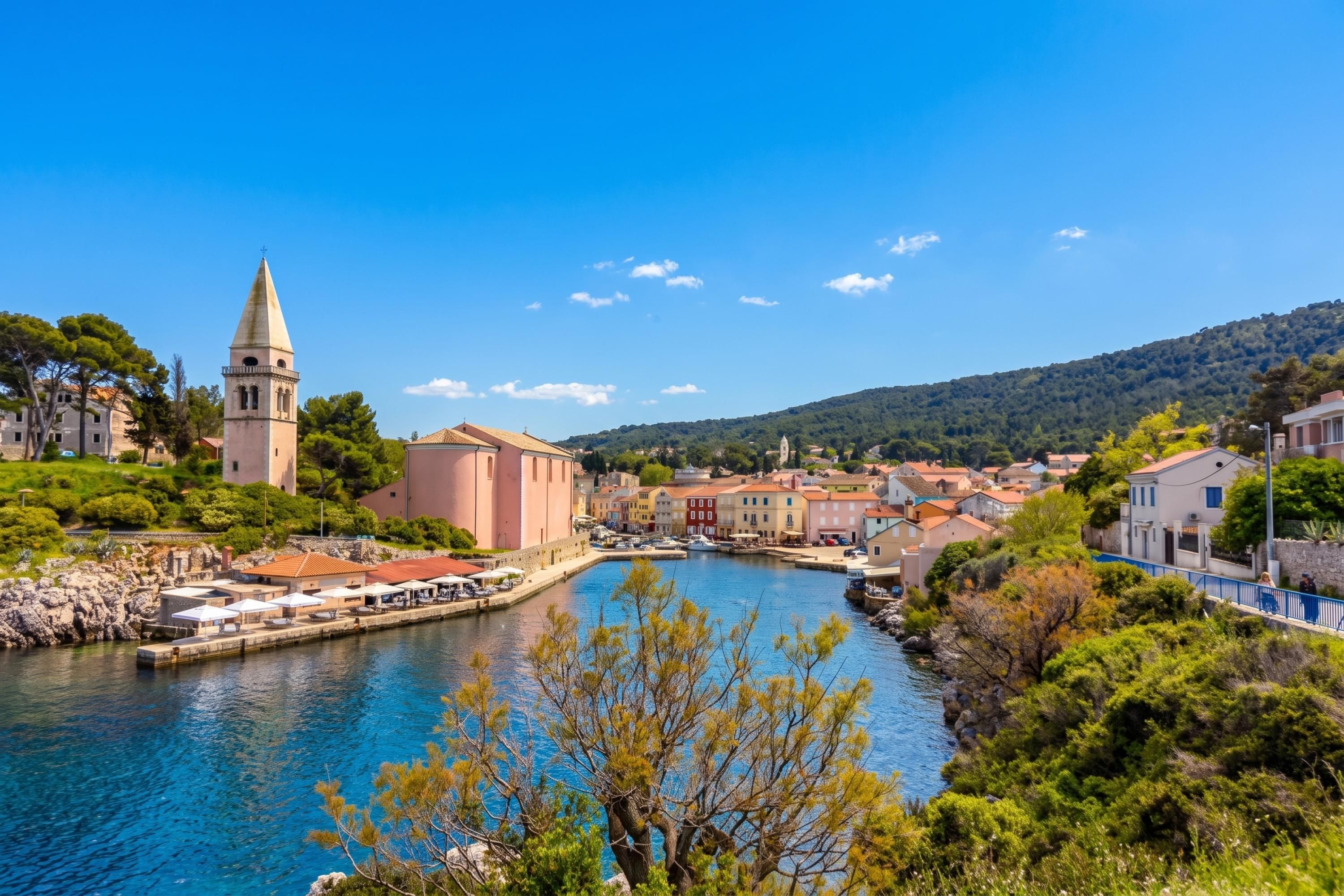 A coastal town with a prominent church, a clear blue sky, and a calm river.