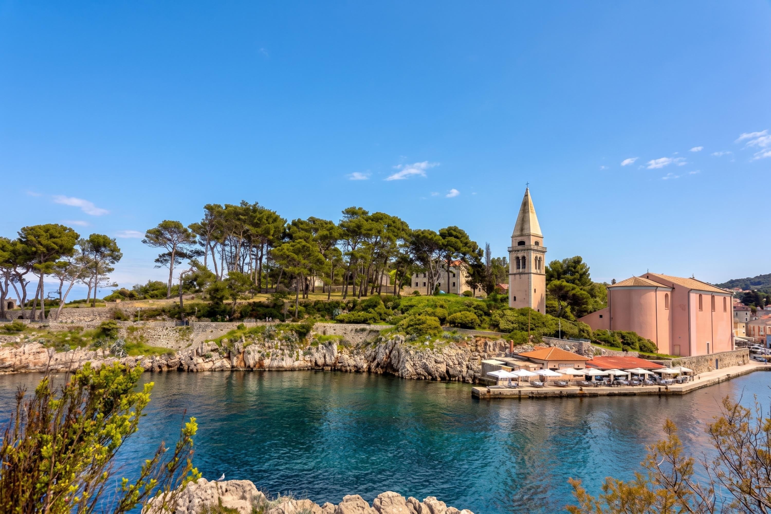 Une ville côtière qui se distingue par son église imposante, son ciel d’un bleu éclatant et sa mer calme.