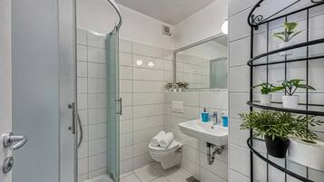 Familie studio, magnetron (Orange Studio Apartment) | Badkamer | Een douche, handdoeken, zeep, shampoo