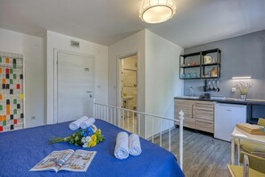 Une chambre d’hôtel comprenant un lit, une petite kitchenette, une salle de bain et donnant sur l’extérieur.