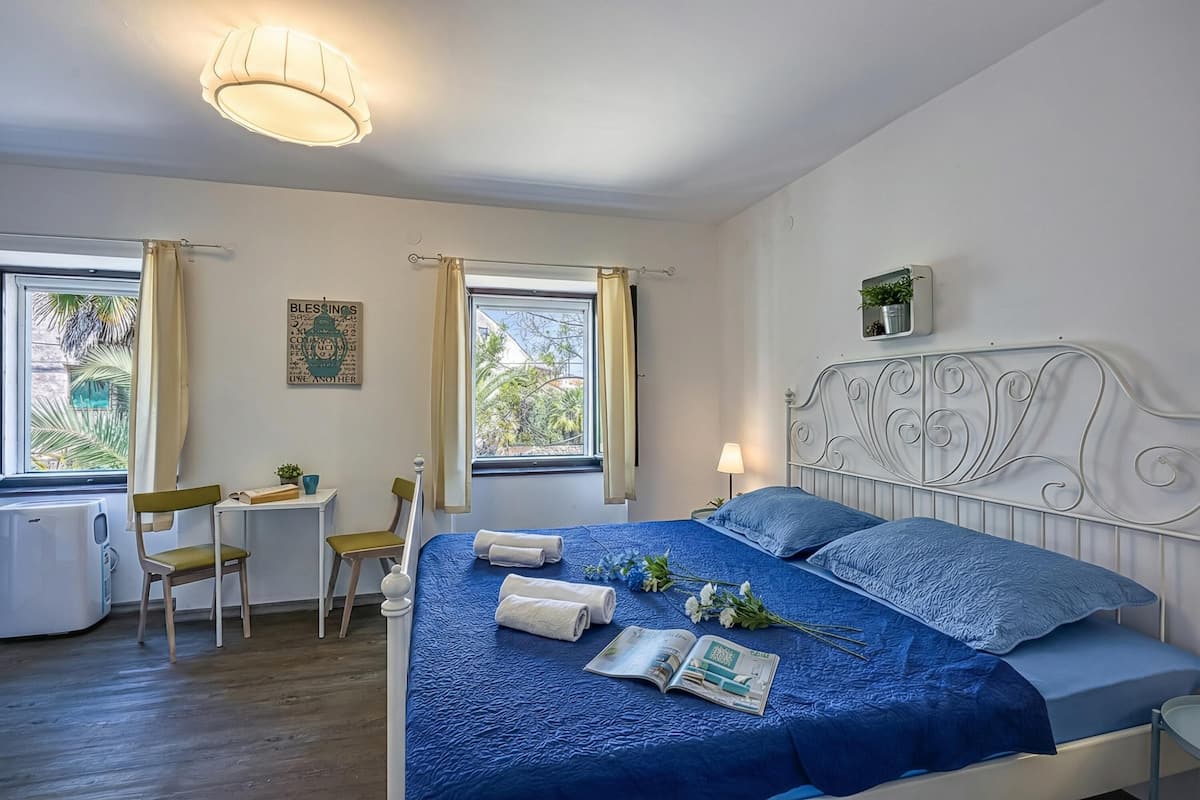 A neatly arranged bedroom with a bed, bedside table, lamp, and a window with curtains.