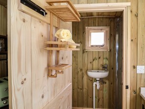 A wooden bathroom with a sink, a window, and a towel hanging on a rack. - The Oak Hut (Whitchurch)