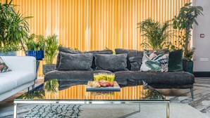 A modern living room with a sofa, coffee table, and potted plants. - The Old Bells (Doncaster)
