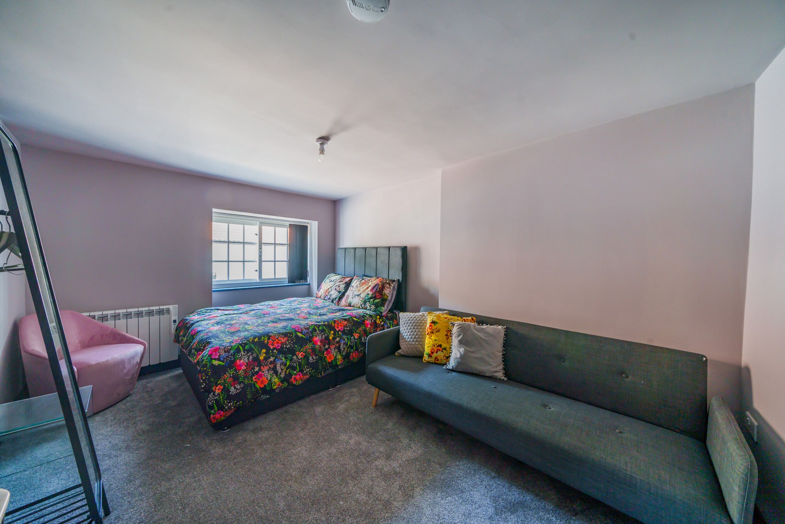 Un dormitorio con cama, sofá, silla y ventana.