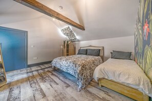 A bedroom with a sloped ceiling, a bed with patterned bedding, a wardrobe, and a door with a blue frame. - The Old Bells (Doncaster)