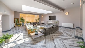 A spacious living area with a modern sofa, a coffee table, and a TV mounted on the wall. - The Old Bells (Doncaster)