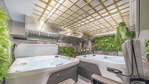 A spa area with two hot tubs, wooden benches, and a ceiling fan. - The Old Bells (Doncaster)