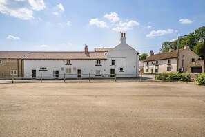 A white building with a tiled roof, a small attached structure, and a gravel courtyard. - The Old Bells (Doncaster)