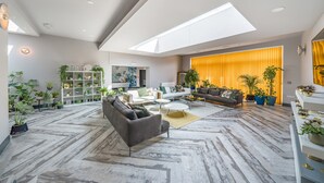 A spacious living area with a high ceiling, skylight, and modern furniture. - The Old Bells (Doncaster)