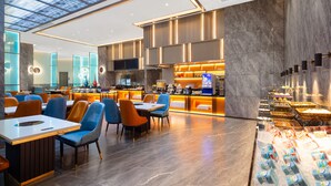 A modern hotel lobby with a central bar area, seating arrangements, and a food display. - Shenzhen Naive S Hotel (Xili Metro Station Store) (Shenzhen)