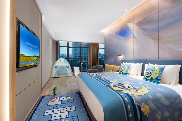 A hotel room with a large bed, a television on the wall, a view of the city, and a small play area.
