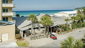 Een hotel aan het strand, met een zichtbaar restaurant genaamd "Shoone's" en een rode golfkar ervoor geparkeerd.