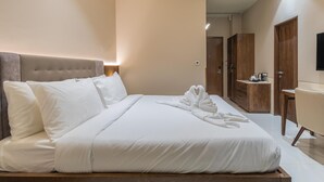 A neatly made bed with white linens, a headboard, and a set of towels on the bed. - MAHARAJA AGRASEN PALACE - PURE VEGETARIAN (Mawal)