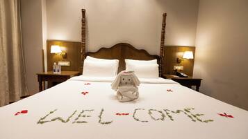 Una habitación de hotel con una cama, un felpudo y un peluche decorativo.