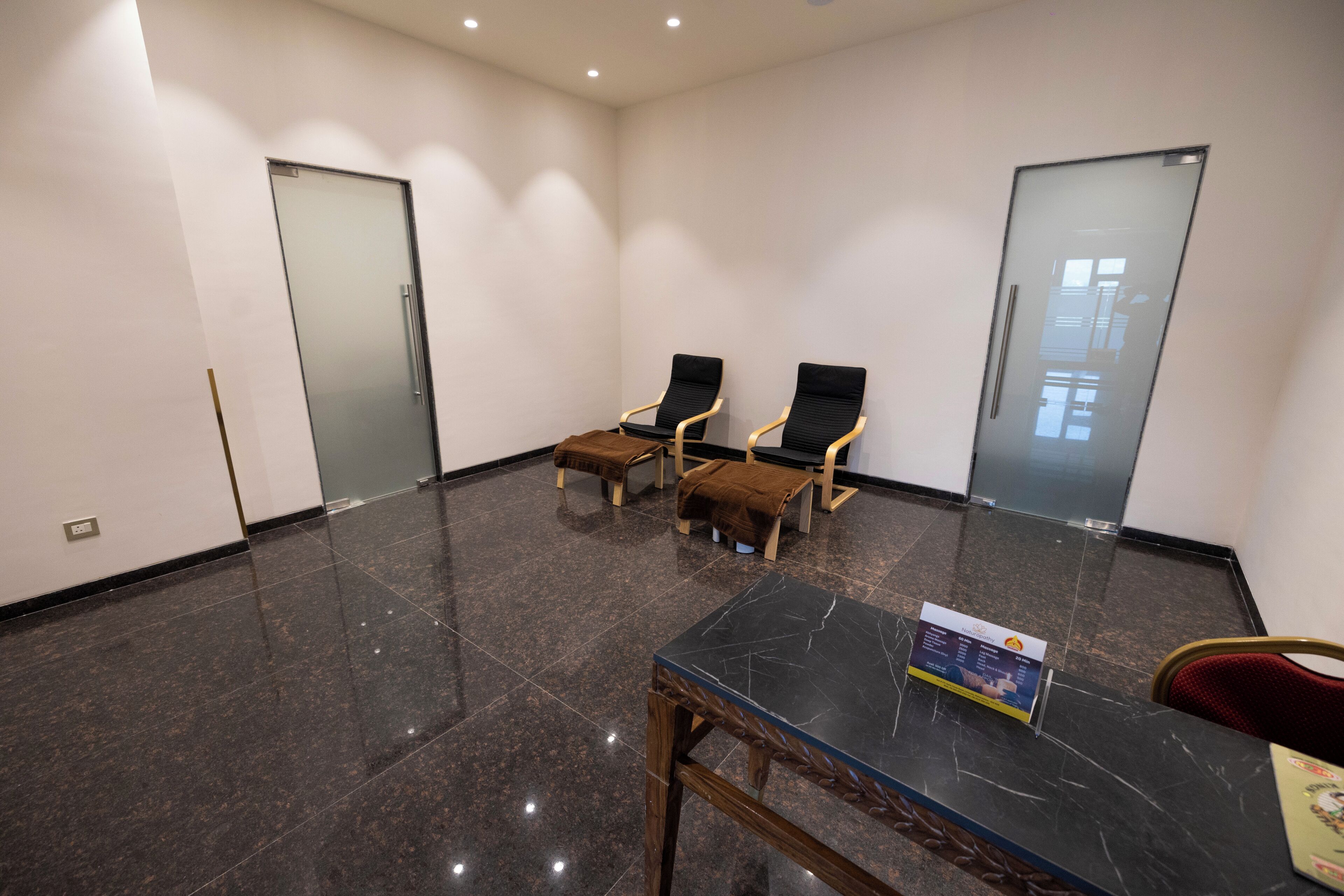 Un salón de conferencias con una mesa de mármol, dos sillas, una mesita y una silla roja.