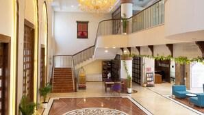 A spacious lobby with a grand staircase, a chandelier, and a reception desk. - MAHARAJA AGRASEN PALACE - PURE VEGETARIAN (Mawal)