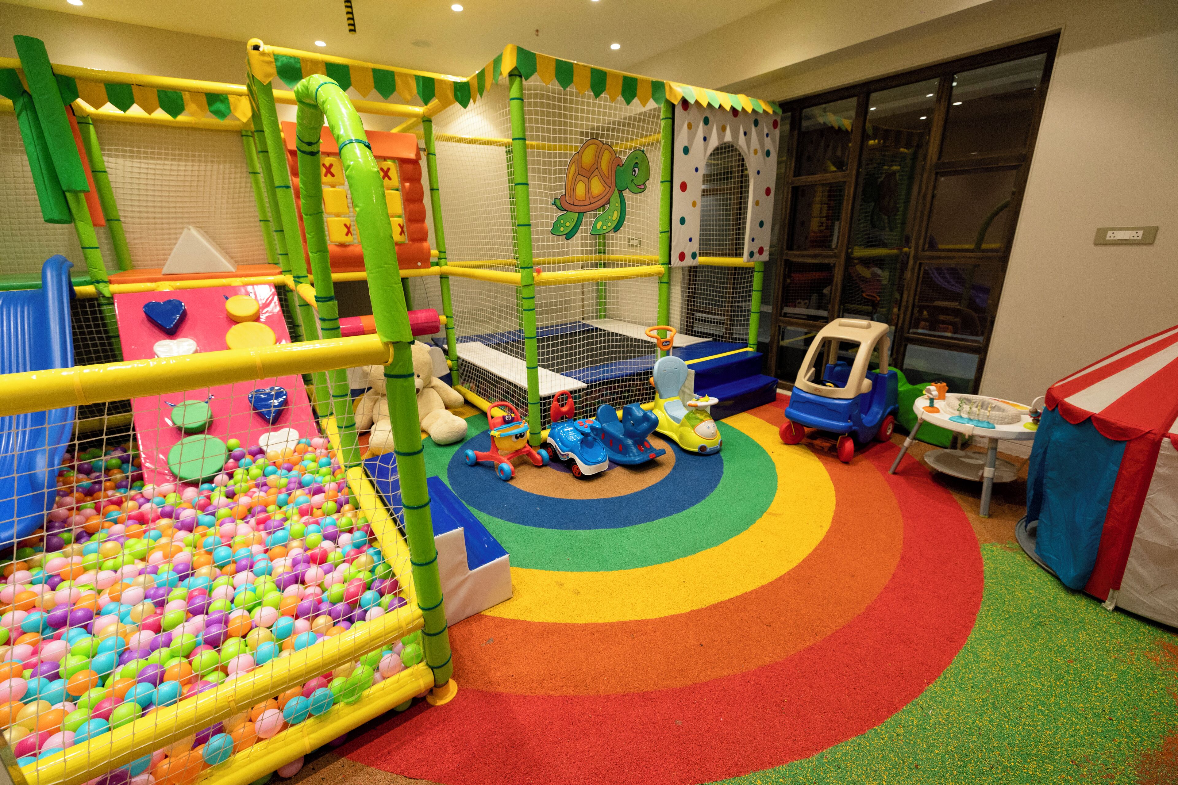 A children's play area with a ball pit, climbing structures, and a small slide.