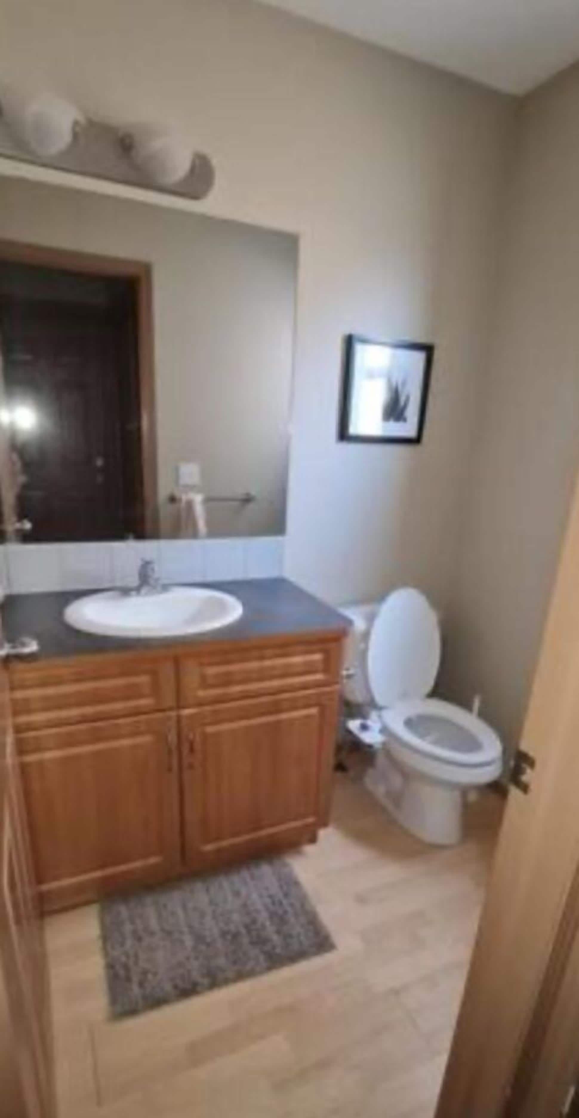 A bathroom with a wooden vanity, a white sink, and a toilet.