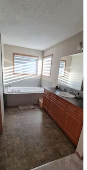 A bathroom with a large bathtub, a sink, and wooden cabinets.