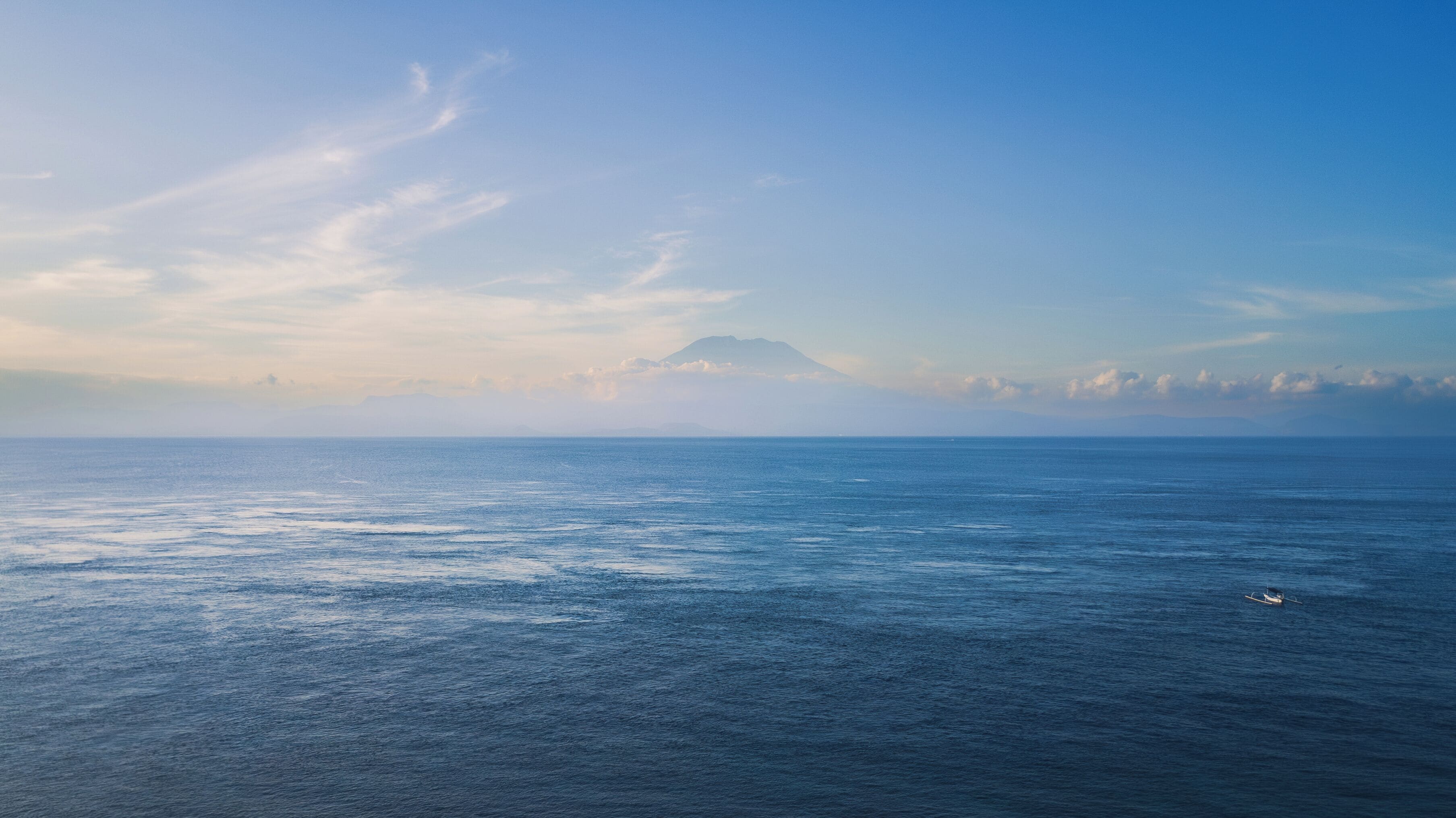 Vista de un mar tranquilo con una montaña distante y un cielo despejado.