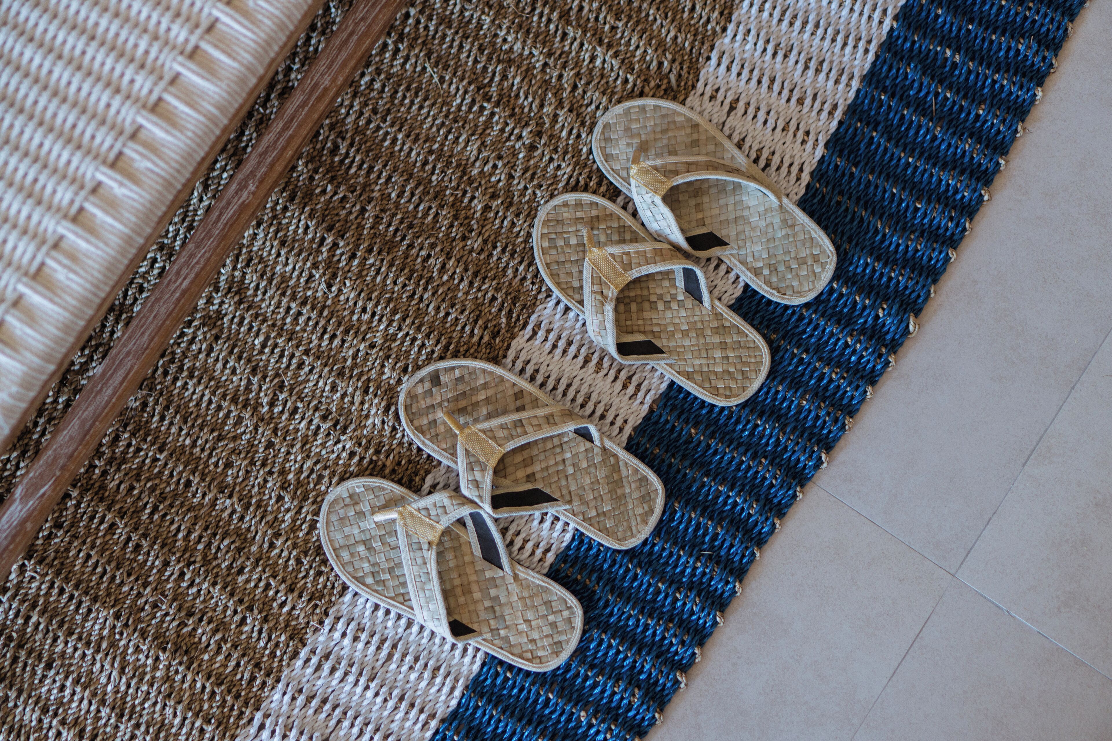 A pair of woven mats and a pair of woven slippers on a floor.