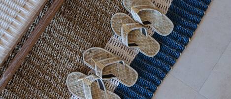 A pair of woven mats and a pair of woven slippers on a floor.