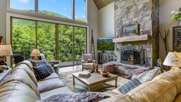 A spacious living room with a stone fireplace, large windows, and a cozy seating area. - Nearly Six Private Acres. A Spring-Fed Trout Pond. Shortoff MountainViews | Shortoff Mountain View (Highlands)