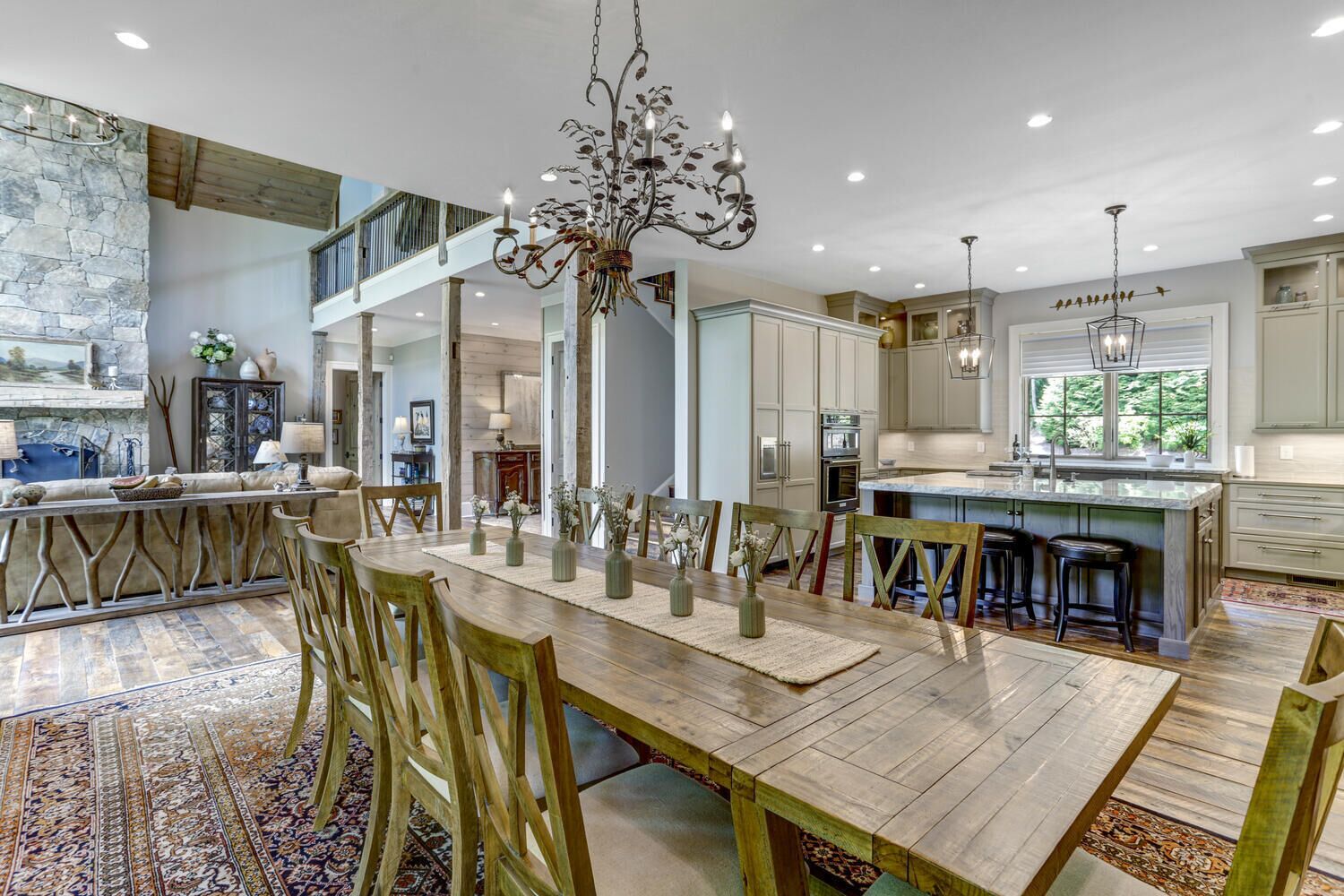 A spacious kitchen with a central island, wooden dining table, and modern lighting fixtures.