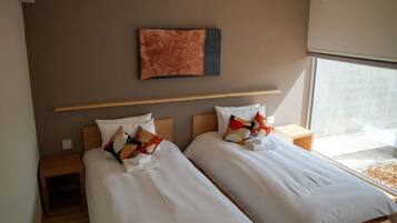 A hotel room with two beds, a wooden headboard, a wall-mounted artwork, and a window with a view.