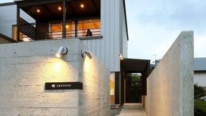 A modern building with a concrete facade, a visible nameplate, and a covered walkway leading to the entrance. - AKATSUKI (Furano)