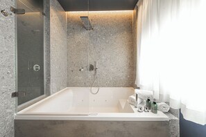 Un bagno moderno con una vasca autonoma, una cabina doccia in vetro e una parete rivestita in marmo.
