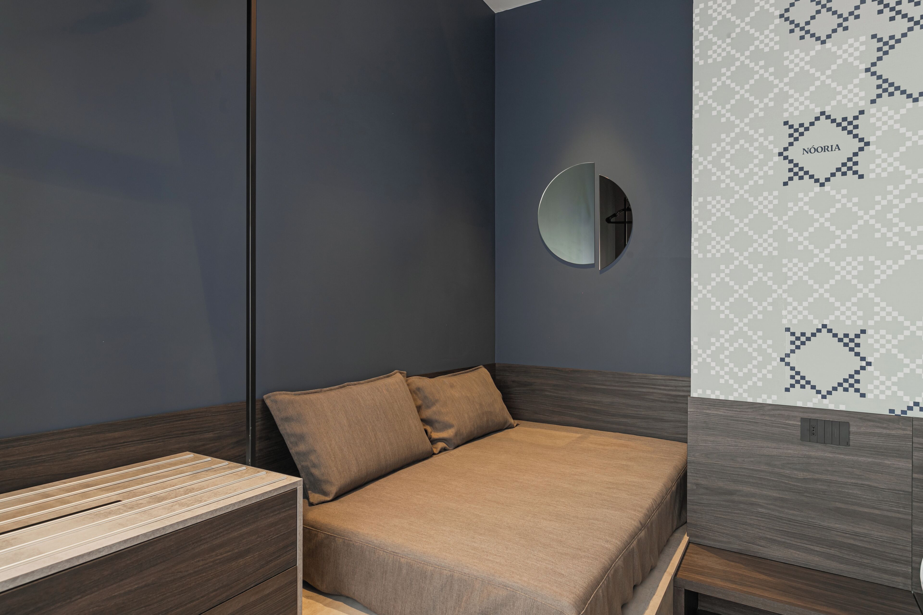 A modern bedroom with a bed, a bedside table, and a wall-mounted mirror.