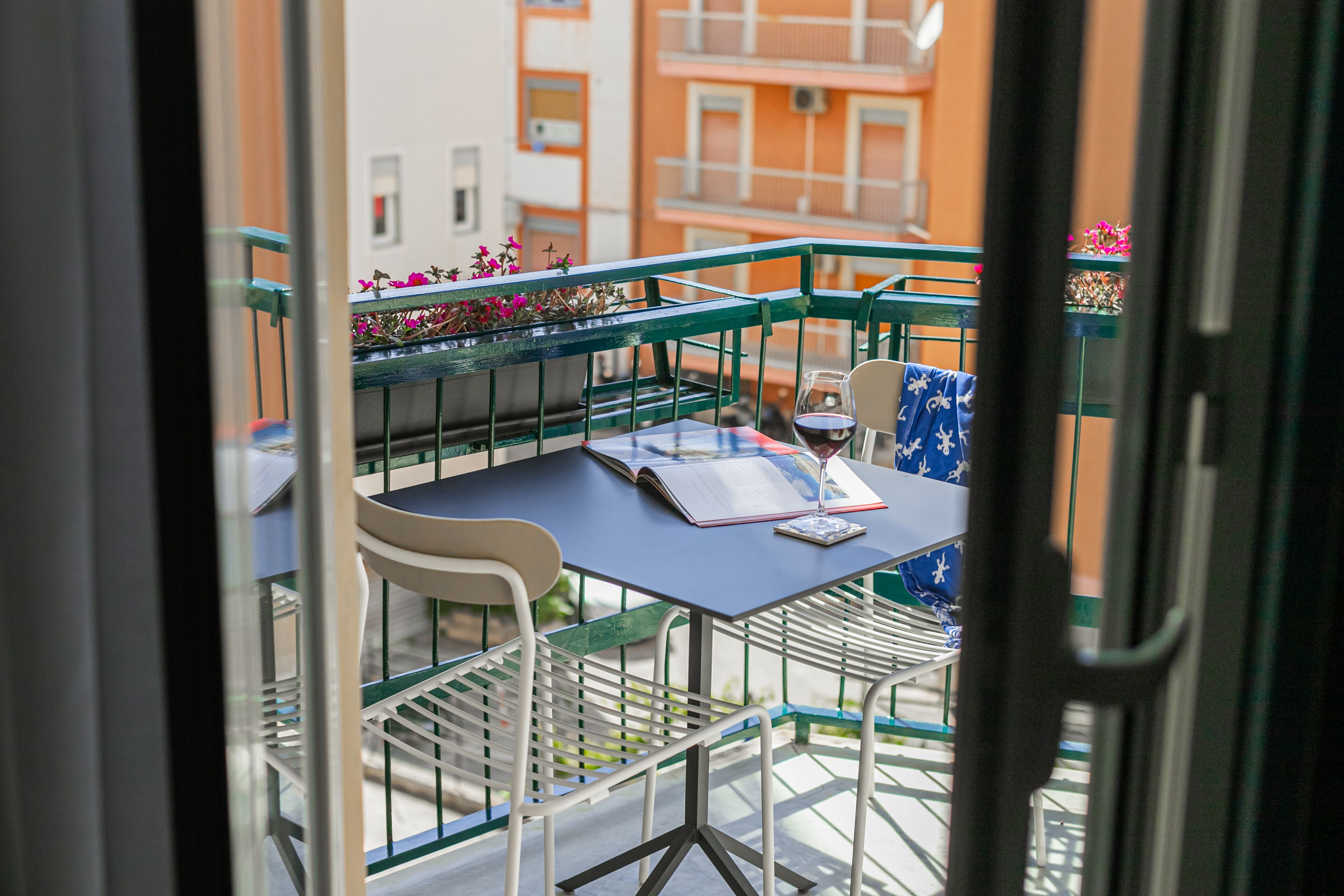 Un balcon avec une table, des chaises et un pot de fleurs.