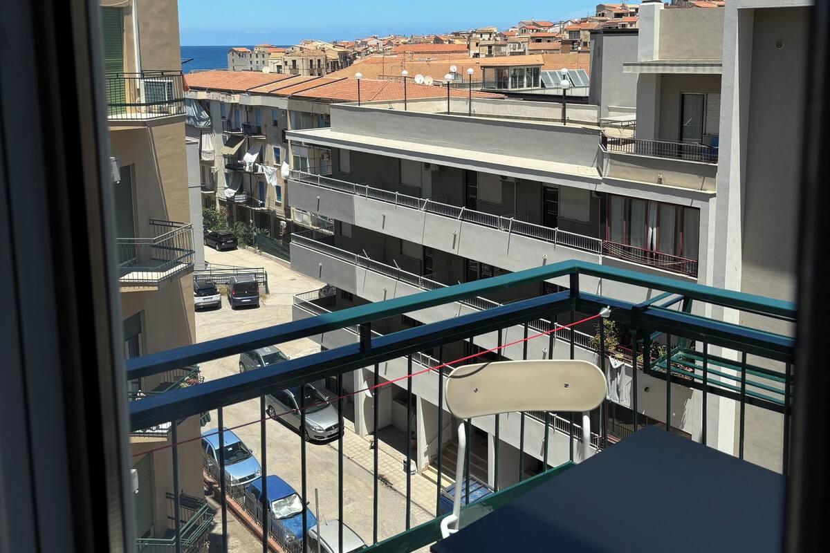 Ein Balkon mit Blick auf ein Wohngebiet, mit Gebäuden und parkenden Autos.