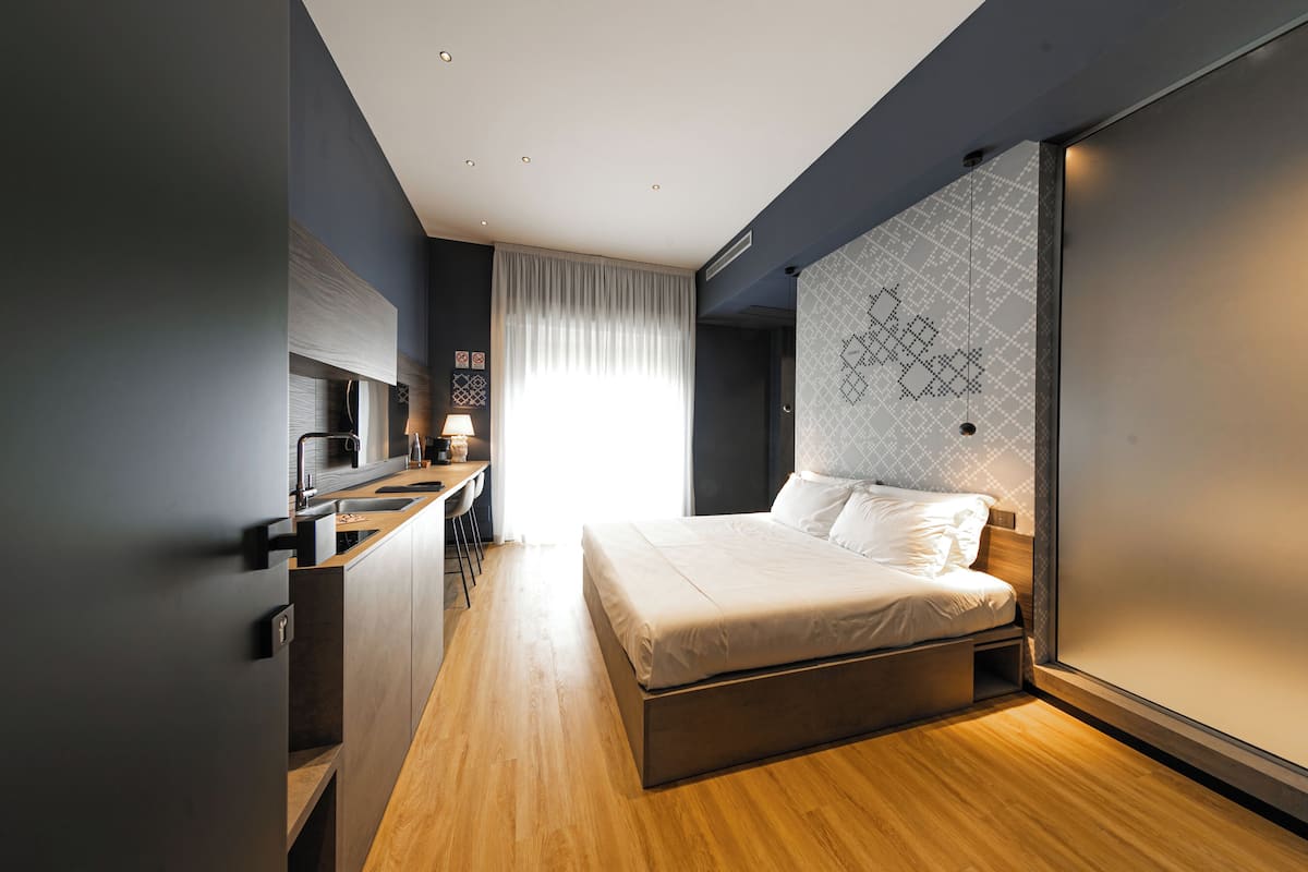 Ein modernes Schlafzimmer mit Bett, Schreibtisch und einem großen Fenster.