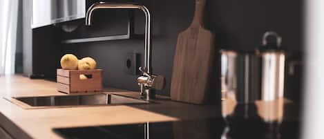 Una cocina moderna con un lavamanos de acero inoxidable, tabla de cortar de madera y un cesto de madera con papas.
