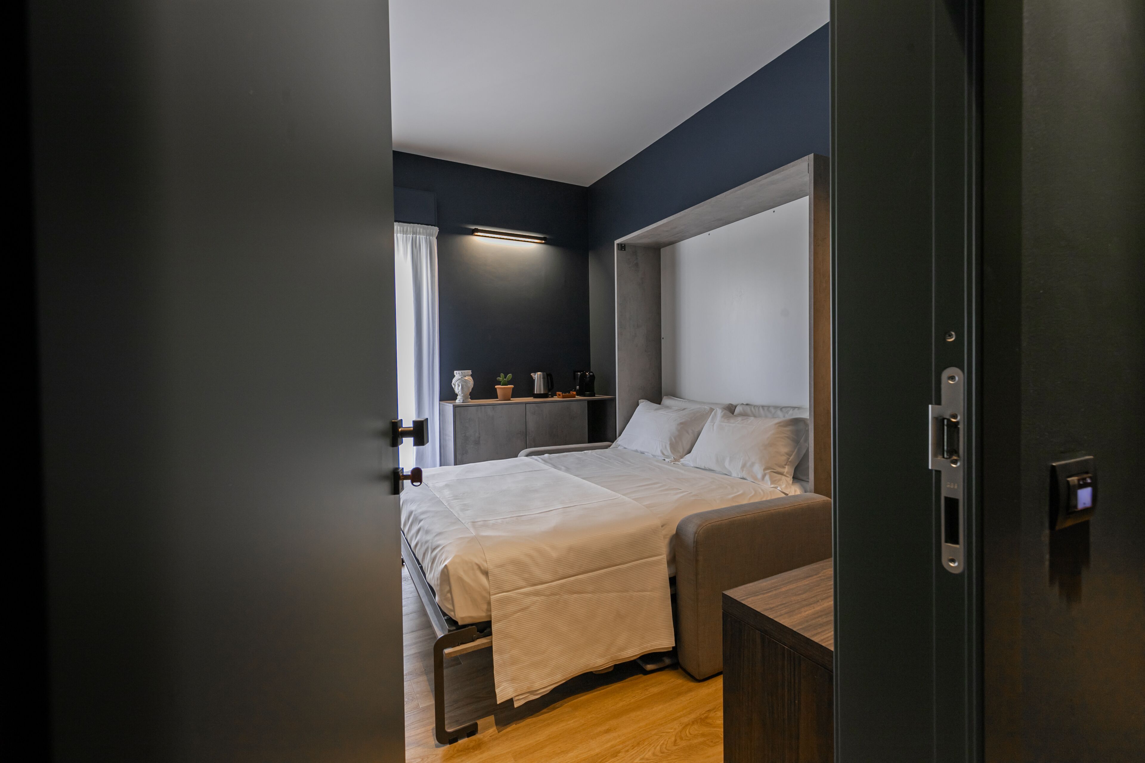 Un dormitorio moderno con cama, mesita de noche y velador.