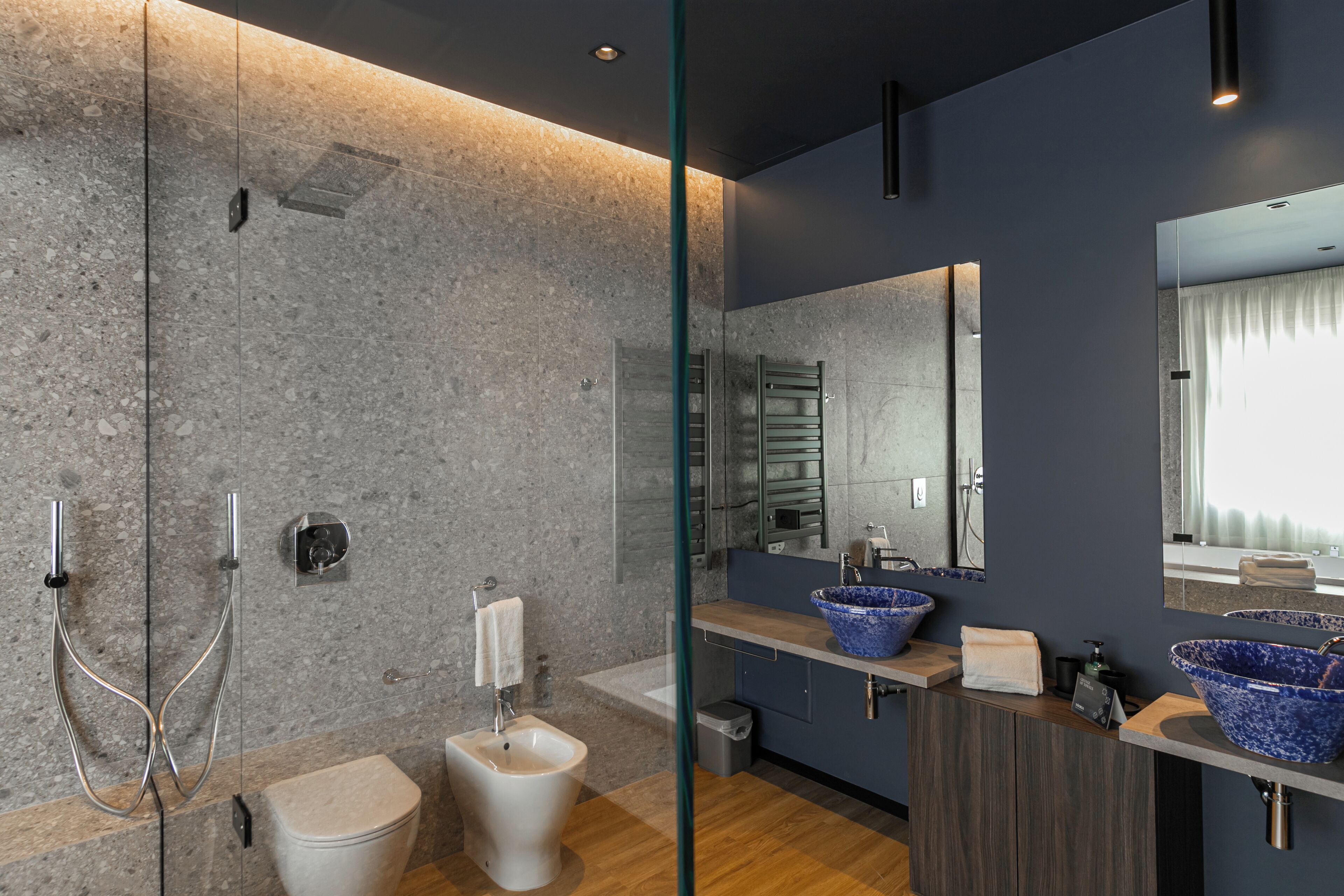Une salle de bain moderne avec un bidet, un grand miroir et un lavabo bleu.