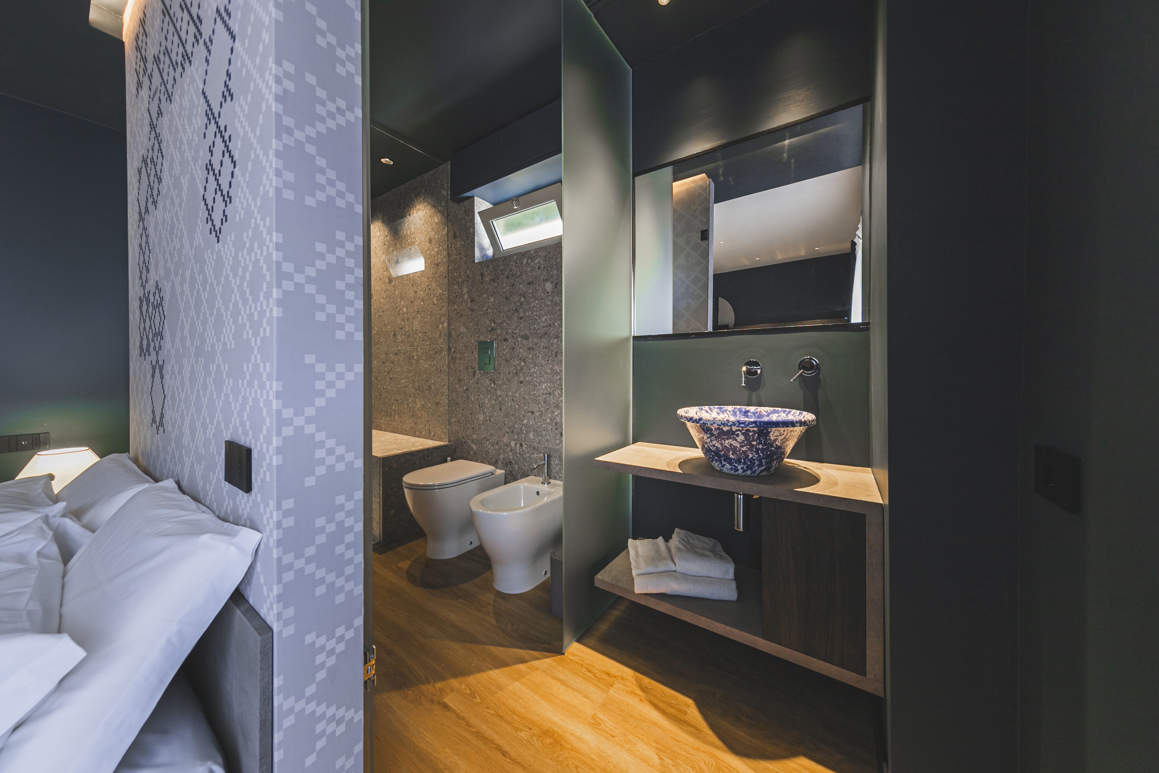 Un baño moderno con un bidé, un espejo grande y un mueble de tocador de madera.