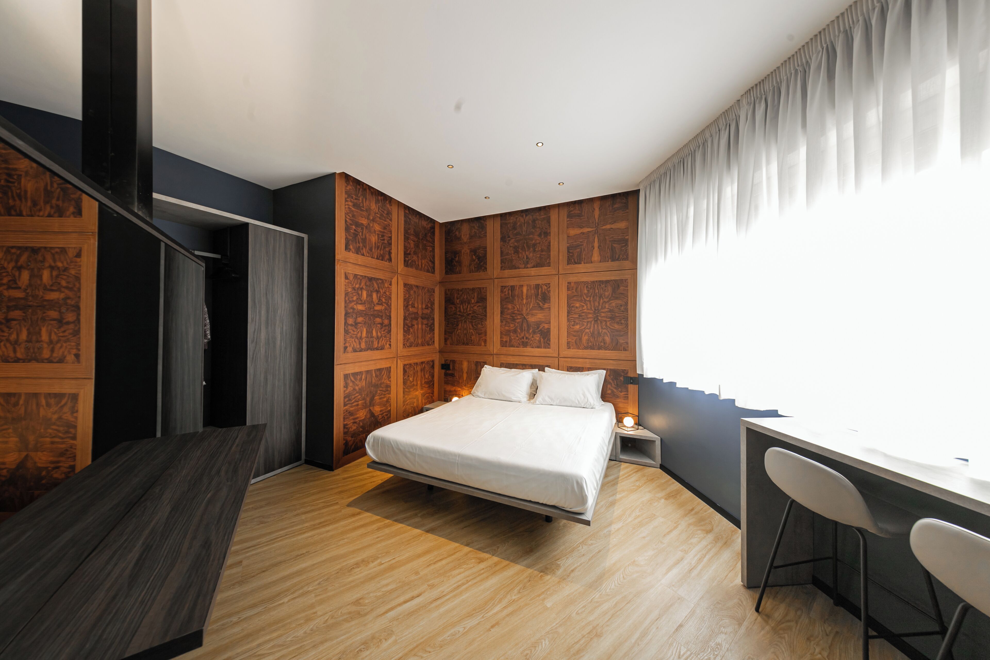 A modern bedroom with a bed, a desk, and a chair.
