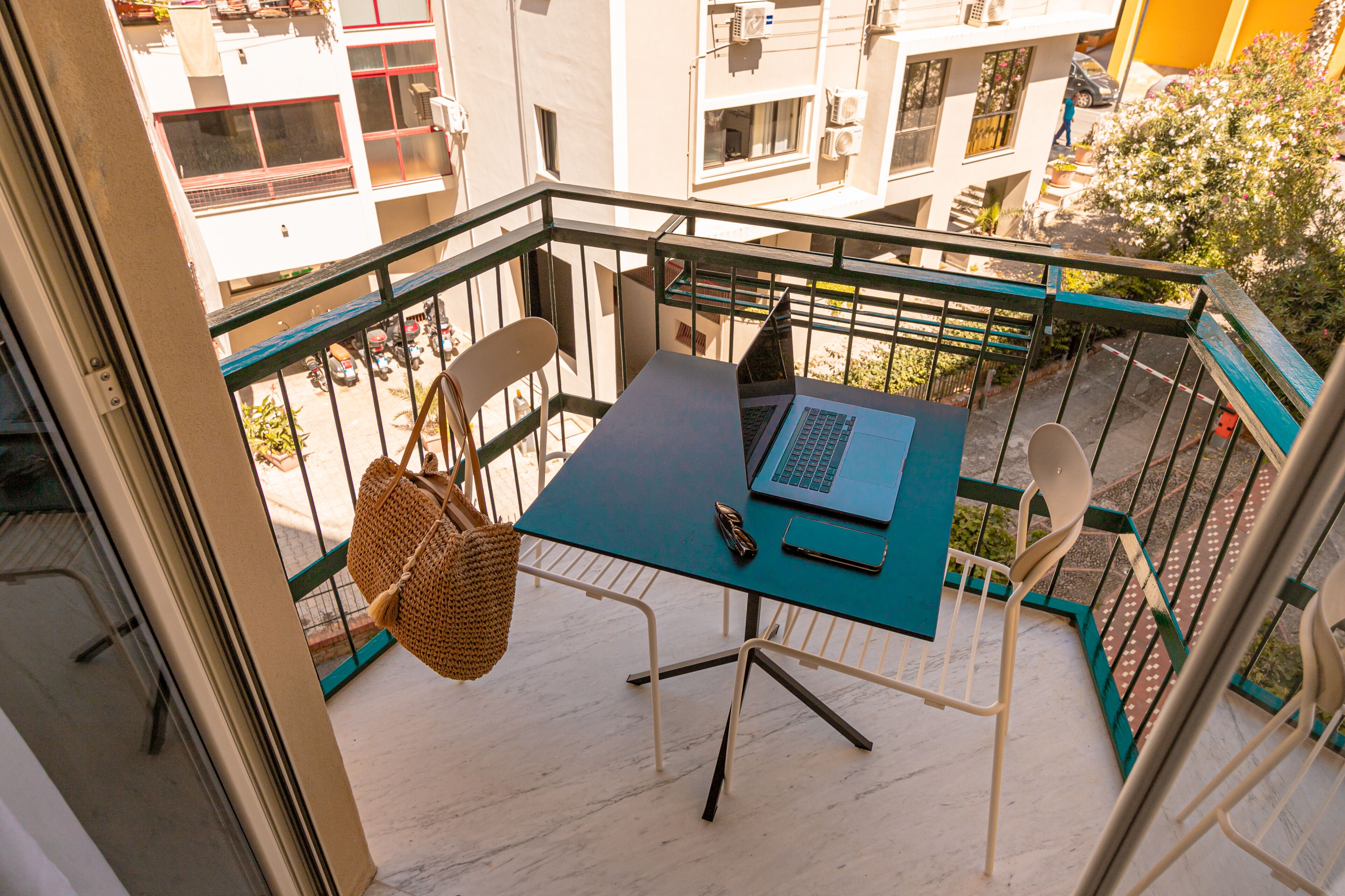 Uma varanda com mesa, cadeiras e um laptop.