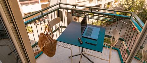 Uma varanda com mesa, cadeiras e um laptop.
