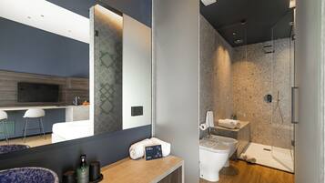 Une salle de bain moderne avec un grand miroir, un lavabo doté d’un receveur bleu, des toilettes et un espace douche.