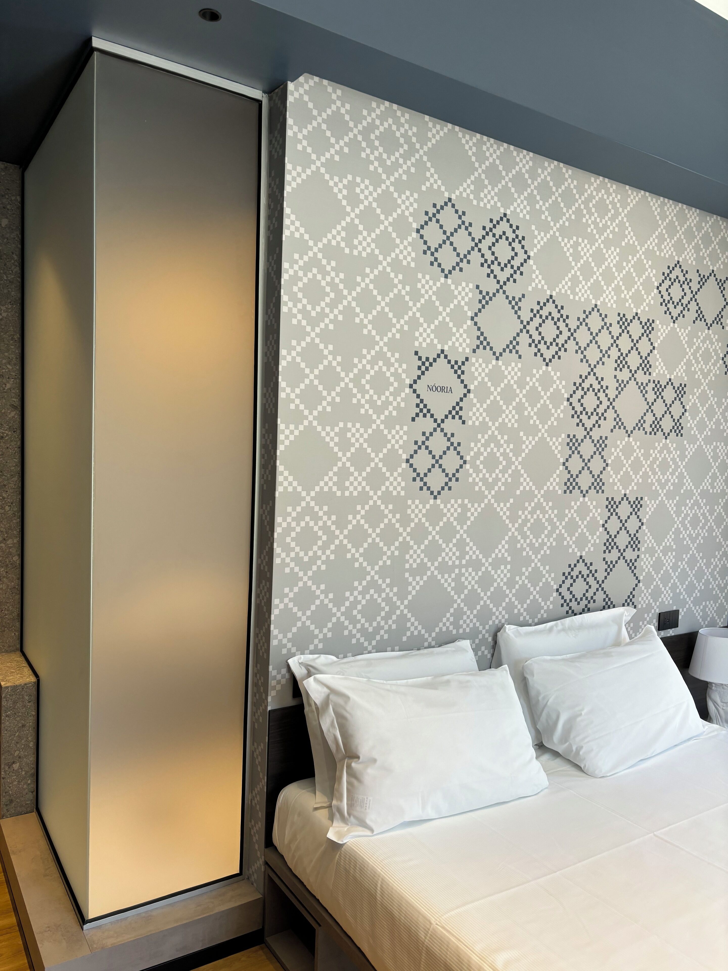 Una habitación de hotel moderna con una cama grande, un armario y una pared con diseño.