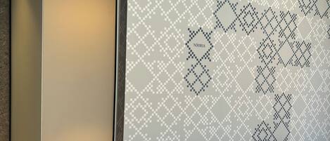 A modern hotel room with a large bed, a wardrobe, and a patterned wall.
