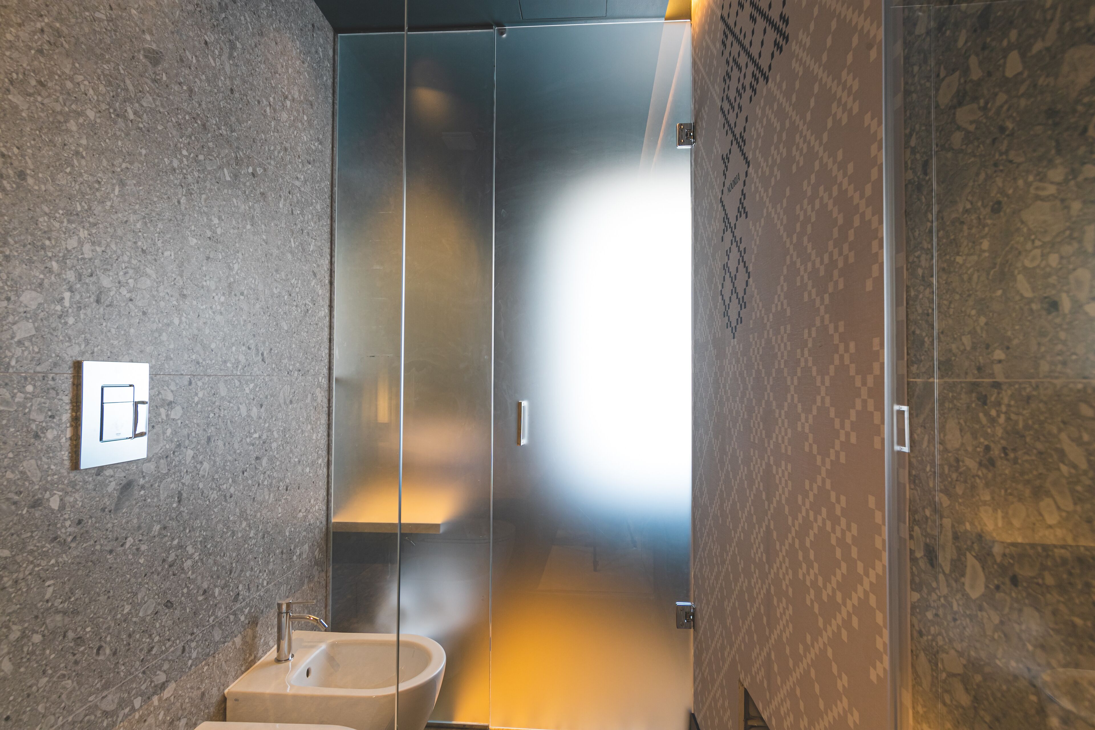 Un baño moderno con cabina de ducha de vidrio, lavamanos y retrete.